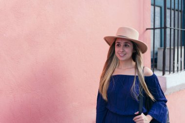 Sırt çantası duvara dönük gülümseyen genç bir kadın.