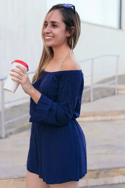 一位女商人一边微笑着 一边拿着一个一次性咖啡杯站在一座商业大楼前 — 图库照片