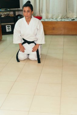 Geleneksel üniformalı Latin bayan atlet evde karate yapıyor..