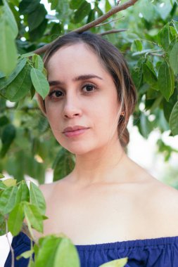 Kadın, yemyeşil bir parkta çeşitli bitkilerle çevriliyken poz veriyor.