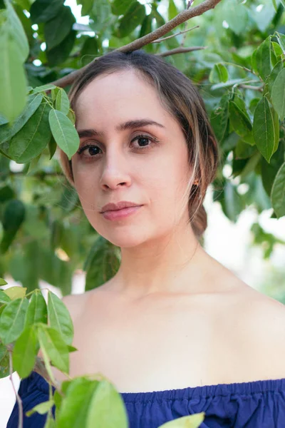 Kadın, yemyeşil bir parkta çeşitli bitkilerle çevriliyken poz veriyor.