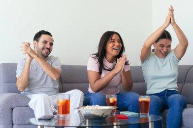 Heyecanlı futbol taraftarları TV izlerken tezahürat yapıyorlar. Genç arkadaşlar partide içki ve abur cubur yiyorlar. Maçın tadını çıkarıyorlar..