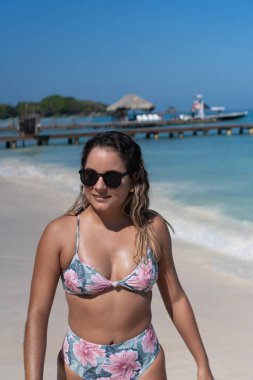 Güneşli sahilde yürüyen İspanyol kadın.