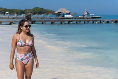 Güneşli sahilde yürüyen güzel genç bir kadın.