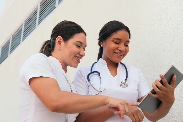 Hispanic Female Doctors Discussing While Looking Digital Tablet — Stockfoto