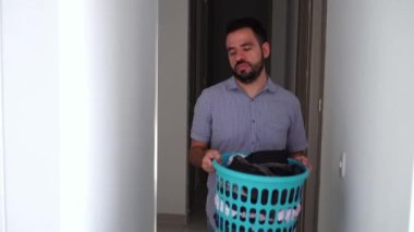 Latin adam evdeki çamaşır makinesine çamaşır koyuyor. Ev İşi ve Temizlik Konsepti