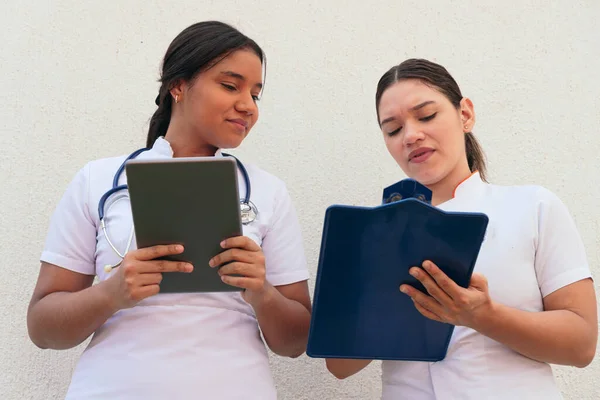 Zwei Latina Krankenschwestern Betrachten Klemmbrett Während Sie Krankenhaus Arbeiten — Stockfoto