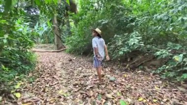 Kuru yapraklarla toprak yolda yürüyen bir adam..