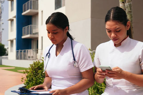 Krankenschwestern Beobachten Ihr Handy Außerhalb Des Krankenhauses — Stockfoto