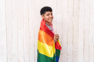 Sembolik LGBTQ çizgilerini temsil eden çok renkli bayraklı Latin kadın