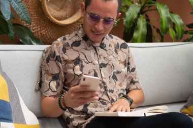 Koltukta oturan bir adam cep telefonunu kontrol ediyor..