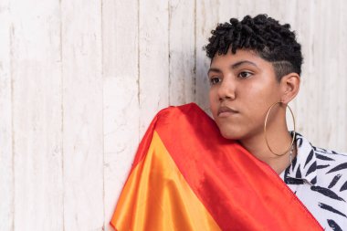 Contemplative woman with LGBT flag outdoors