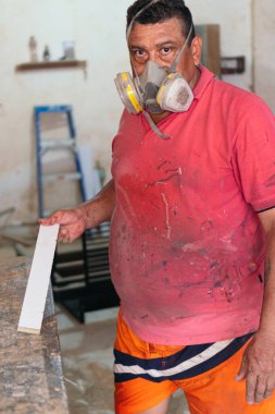 Latin Carpenter in front of a woodworking machine in a carpentry shop, turning a piece of wood.