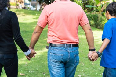 Tanımlanamayan bir baba, çocukları el ele tutuşmuş bir şekilde tarlada yürüyor.