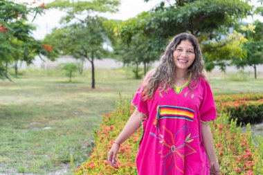 Portrait of Indigenous woman walking in traditional clothing in city park.
