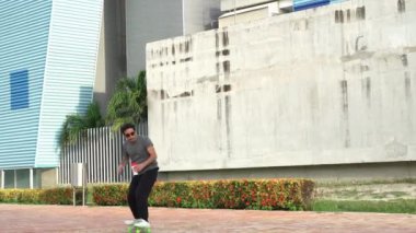 Young man riding a skateboard and carrying a drink