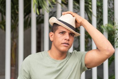 Portrait of a man with freckles wearing a hat in the street.