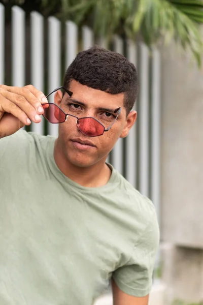 Latin man lowering his sunglasses to his nose to see something