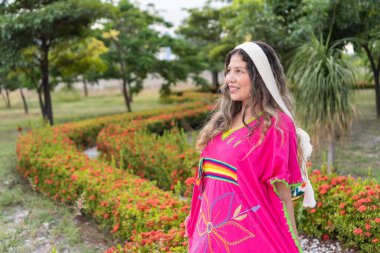 indigenous girl dressed in typical Andean clothing, posing for a camera in the park.