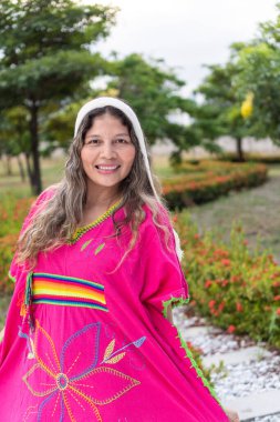 Portrait of a young indigenous girl dressed in typical Andean clothing, posing for a camera in the park.