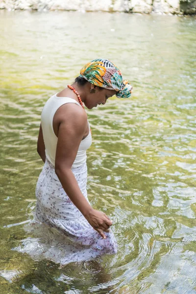 stock image Young woman enters a river in the forest.