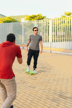 Kaykay yaparken başka bir adamı filme alan adam.