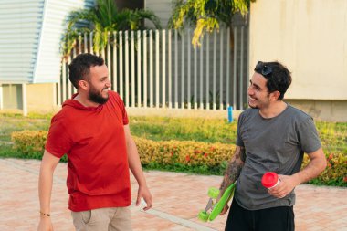 İki genç Latin üniversite öğrencisi parkta birbirlerini selamlıyorlar.