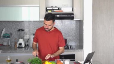 Aşçı evde yemek pişirirken bir video görüşmesi yapıyor.
