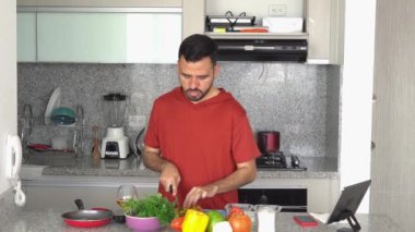 Adam evde yemek pişirirken telefona cevap veriyor.