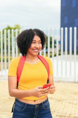 Parkta sırt çantası ve cep telefonu olan Afro Kadın