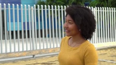 Parkta kulaklıkla müzik dinleyen Afro kadın.