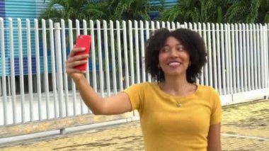 Parkta gülümseyen ve selfie çeken Afrikalı Amerikalı bir kız.