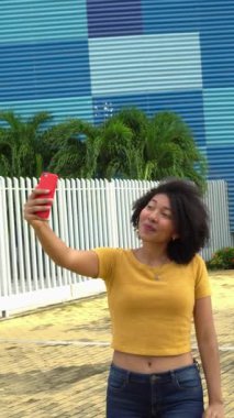 Parkta gülümseyen ve selfie çeken Afro-Amerikan bir kızın portresi.