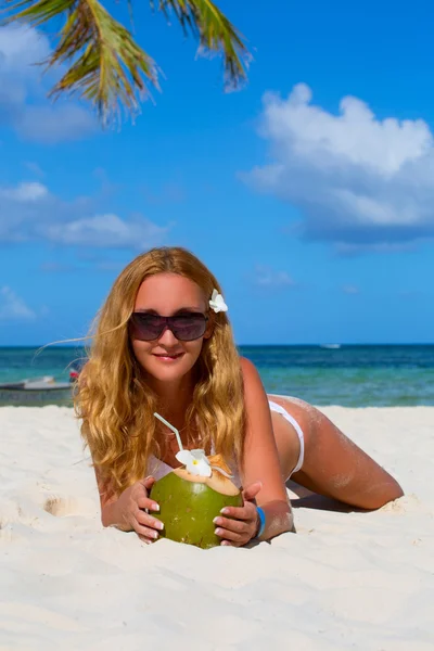 Menina deitada na praia com coco em suas mãos — Fotografia de Stock