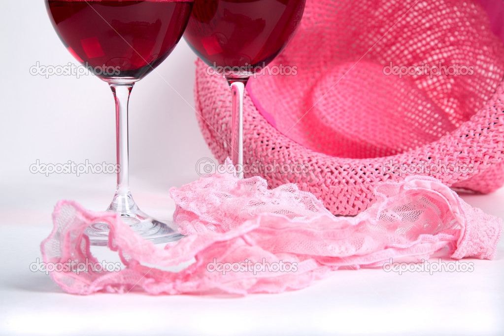 two glasses of red wine on a white background near pink panties 