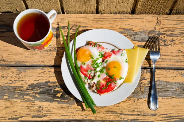 Tasse Tee, Eier, grüne Zwiebeln und Tomaten auf alten hölzernen Tablett — Stockfoto
