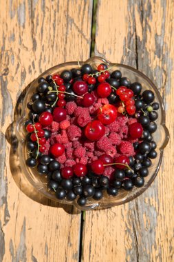 kiraz kuş üzümü ahududu ahşap bir masa üzerinde bir cam tabak