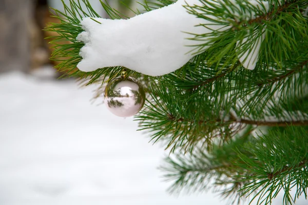 Kugeln hängen an einem Weihnachtsbaum, der mit Schnee bedeckt ist — Stockfoto
