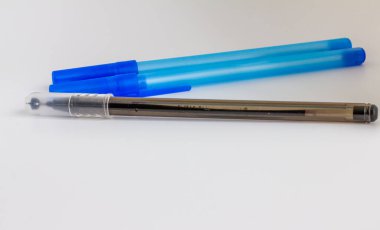 Mavi ve siyah kapaklı 3 tükenmez kalem, beyaz arka planda izole edilmiş.