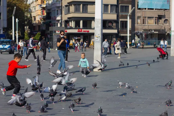 Beyolu, İstanbul, Türkiye-Ekim-Cumartesi-2021: Taksim Meydanı 'nda kuşlar ve koşan çocuklar. Avrupalı kadın fotoğraf çekiyor