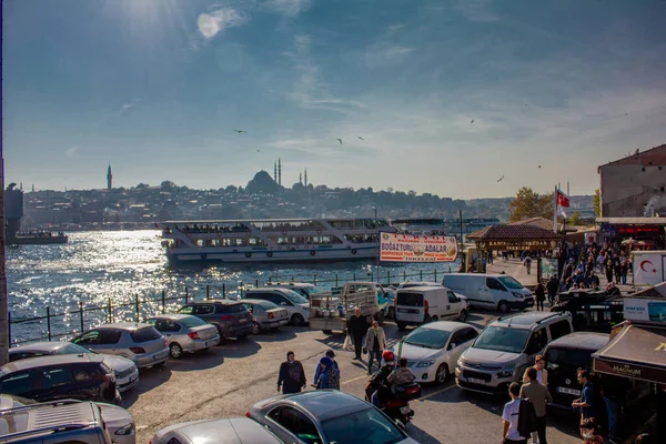Eminonu, İstanbul, Türkiye-Ekim-Cumartesi-2021: Bulutlu hava, park edilmiş arabalar. Eski evlerin arasında yürüyen insanlar. Graffiti çizimi. Golden Horn Metro Köprüsü manzarası ve uçan martılar