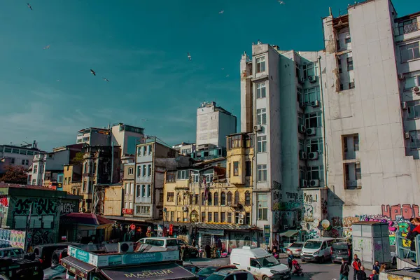 Eminonu, İstanbul, Türkiye-Ekim-Cumartesi-2021: Bulutlu hava, park edilmiş arabalar. Eski evlerin arasında yürüyen insanlar. Graffiti çizimi. Golden Horn Metro Köprüsü manzarası ve uçan martılar