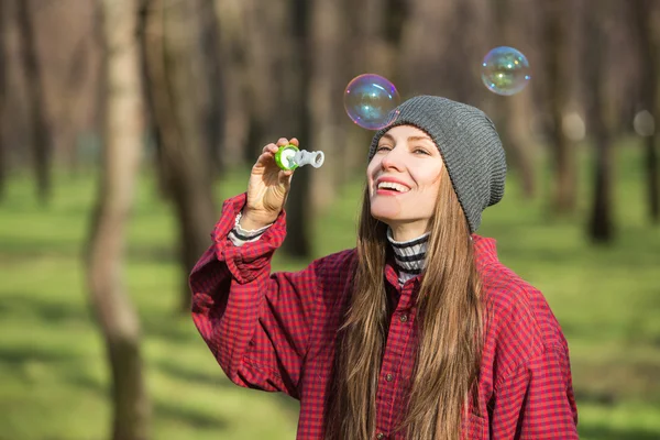 Mujer joven soplando burbujas al aire libre — Foto de Stock