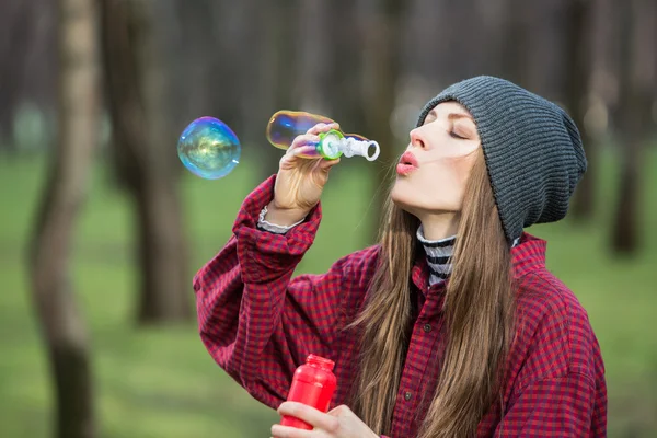 Mladá žena foukání bublin venku — Stock fotografie