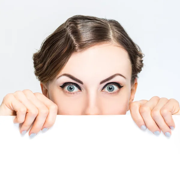 Woman peeking out from behind billboard paper poster — Stock Photo, Image