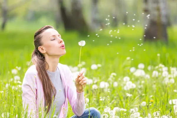 Happy beautiful woman blowing dandelion — Stock Photo, Image