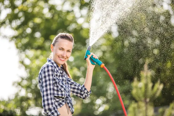 Sommar trädgård kvinna vattna gräsmattan — Stockfoto