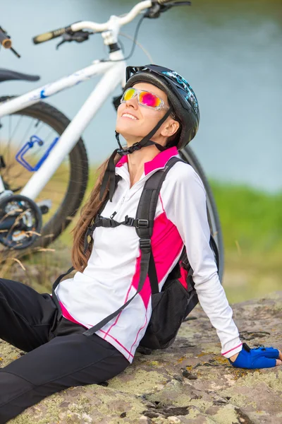 Спортивная улыбающаяся девушка, сидящая рядом с велосипедом — стоковое фото
