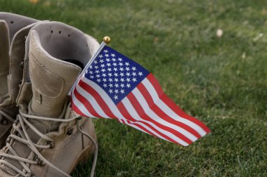 Rüzgarda sallanan bir Amerikan bayrağının sembolü olarak evine dönen bir Amerikan askerinin çizmeleri.