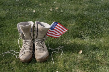 Rüzgarda sallanan bir Amerikan bayrağının sembolü olarak evine dönen bir Amerikan askerinin çizmeleri.